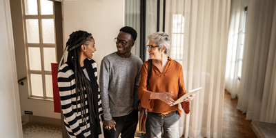 smiling couple walking through at house with a realtor